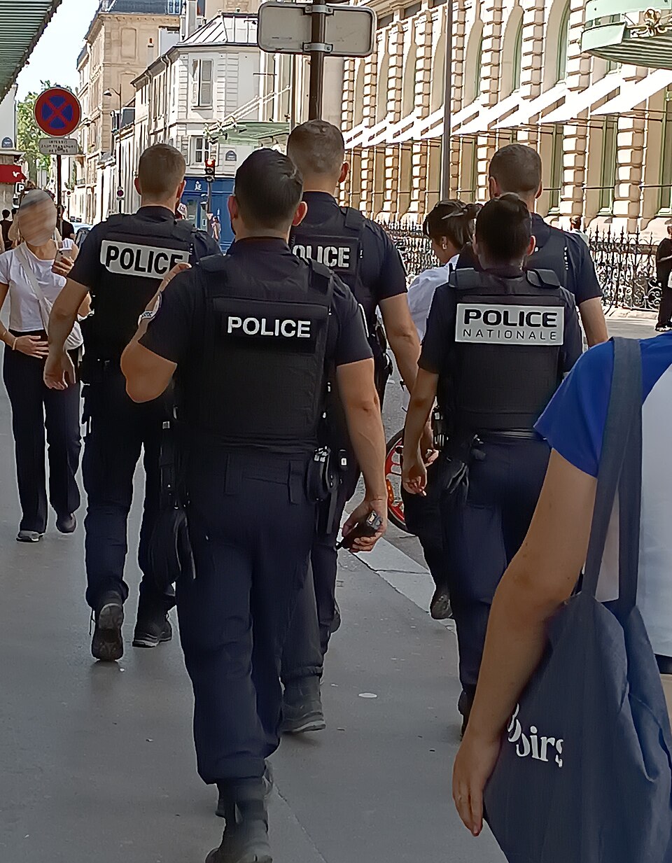Policiers de la Police nationale vus de dos lors d’une patrouille à Paris en août 2024. Photographie d’archives.