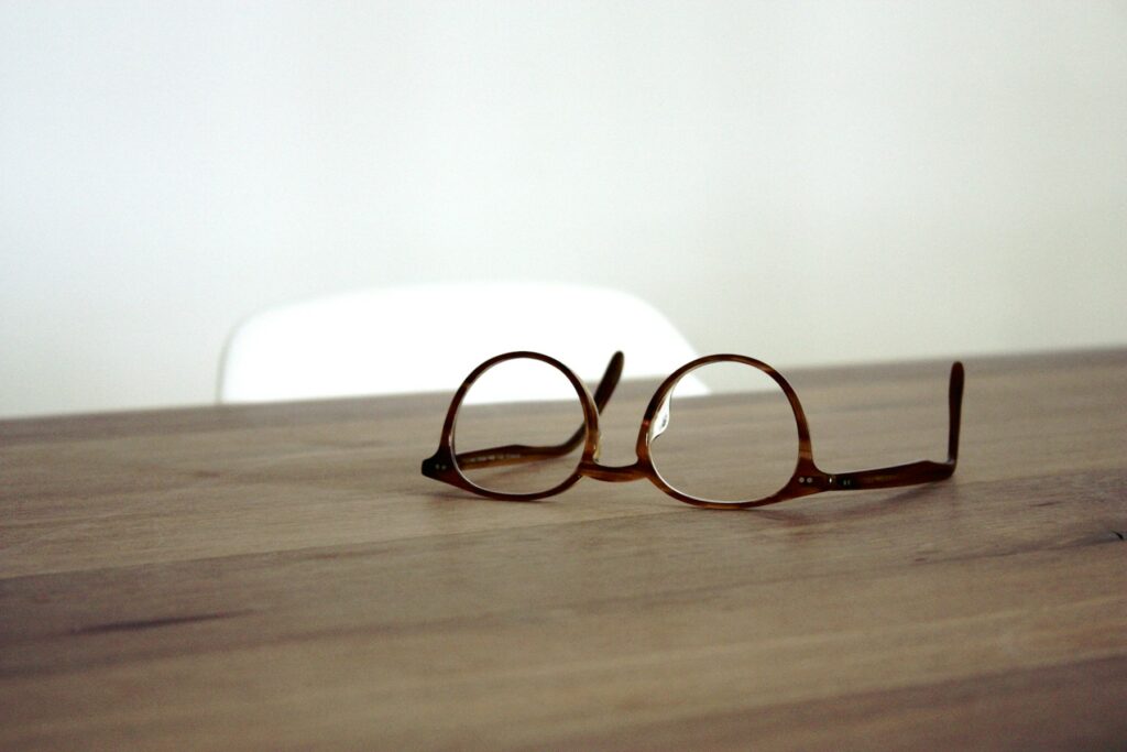 Une paire de lunettes à monture ronde posée sur une table en bois.