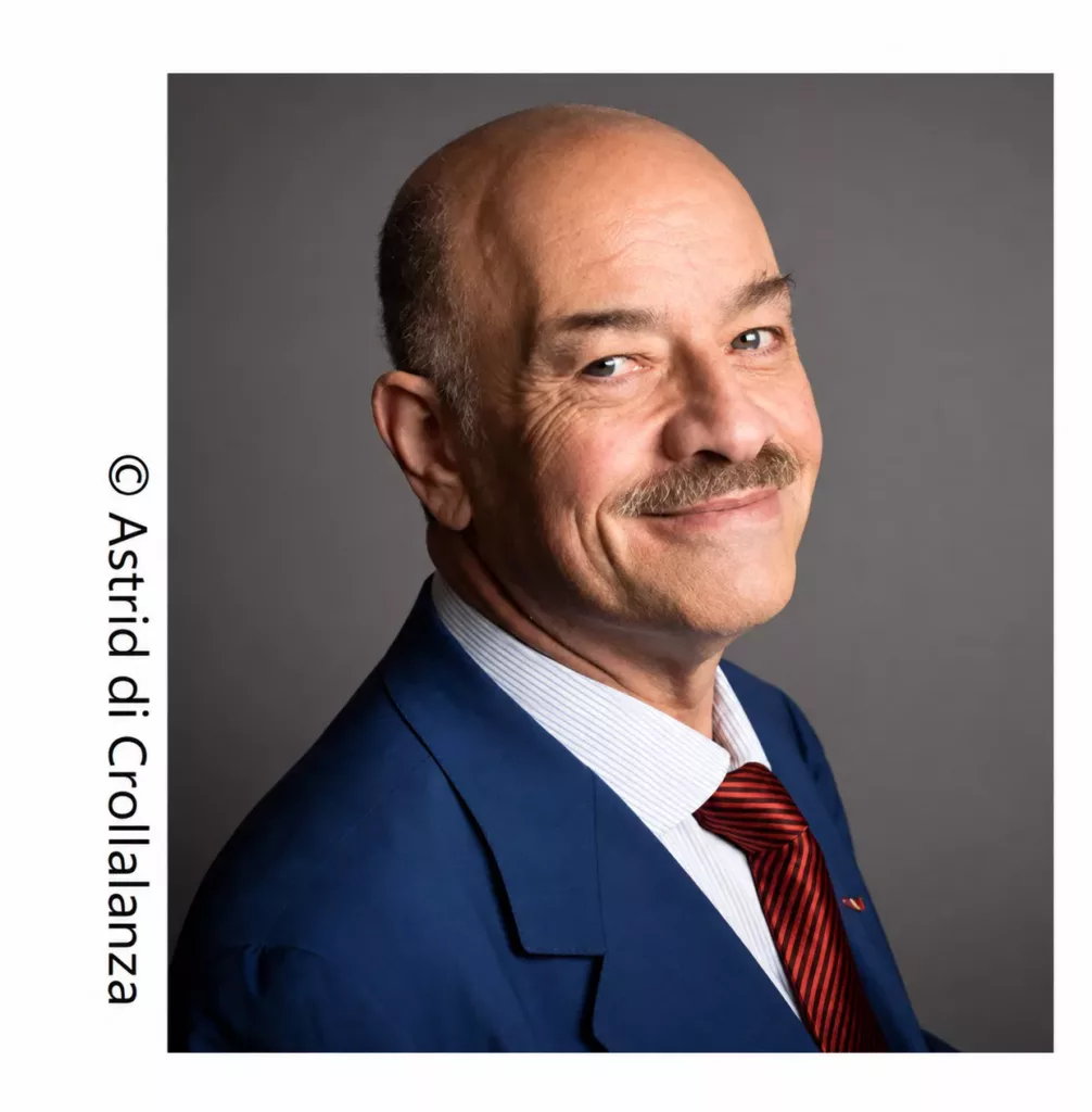 Alain Bauer, portrait en couleur en costume bleu et cravate rouge. Photo : Astrid di Crollalanza.