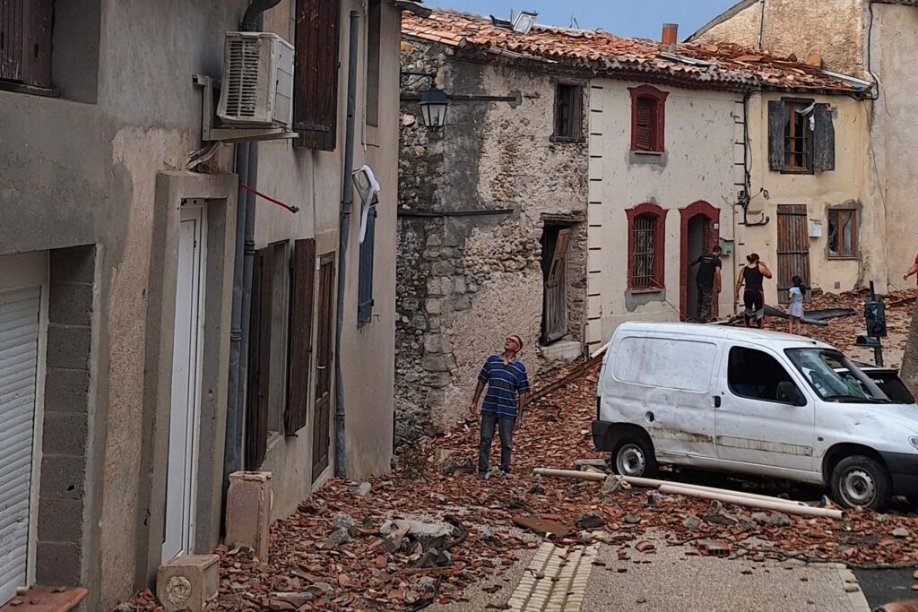 Pomas : Les gendarmes ont été extraordinaires ! Une rue de Pomas jonchée de tuiles après la tornade du 24 août, avec des habitants devant les maisons endommagées.