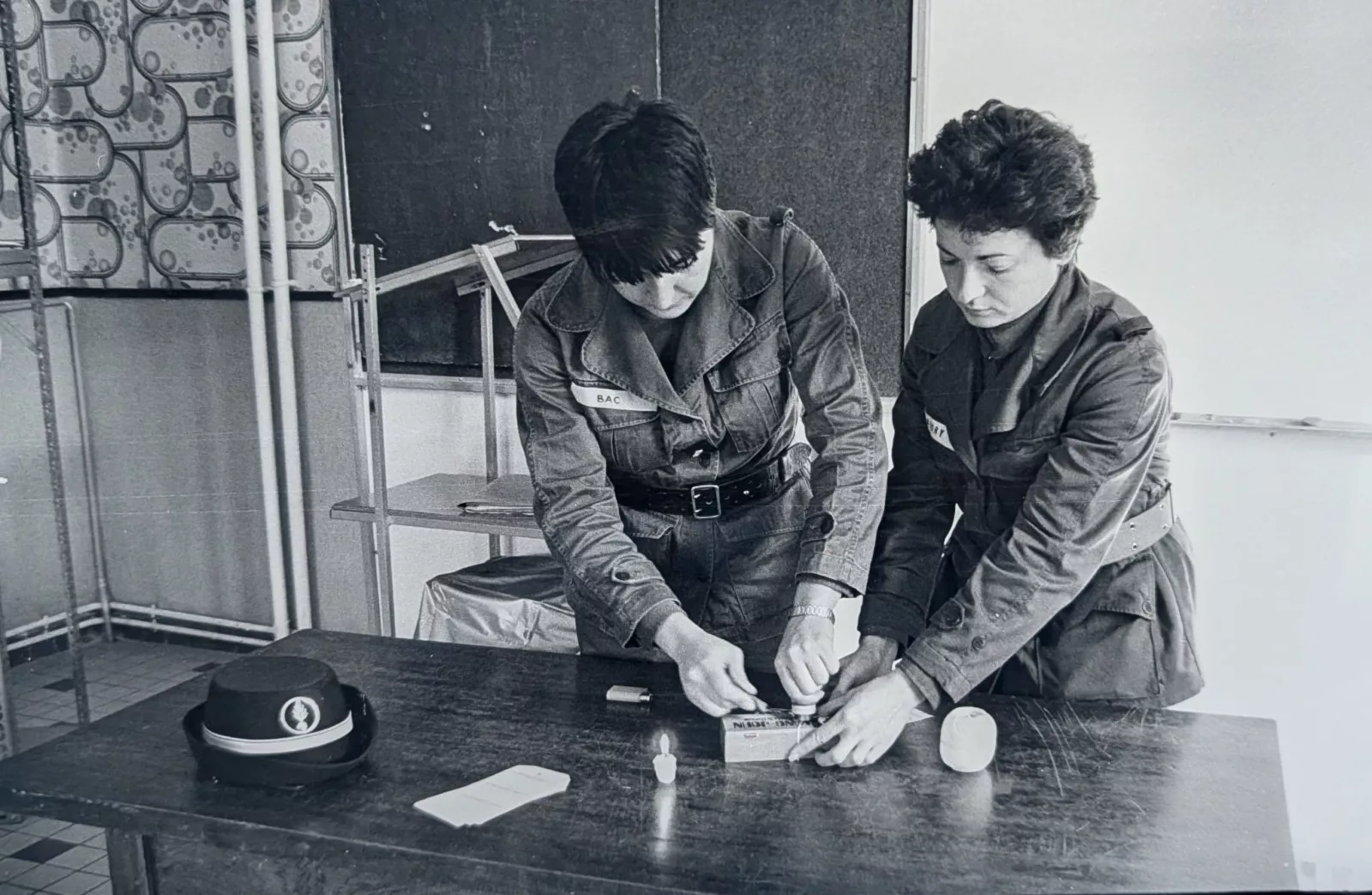 Deux femmes en uniforme effectuent ensemble un exercice pratique autour d’une table.